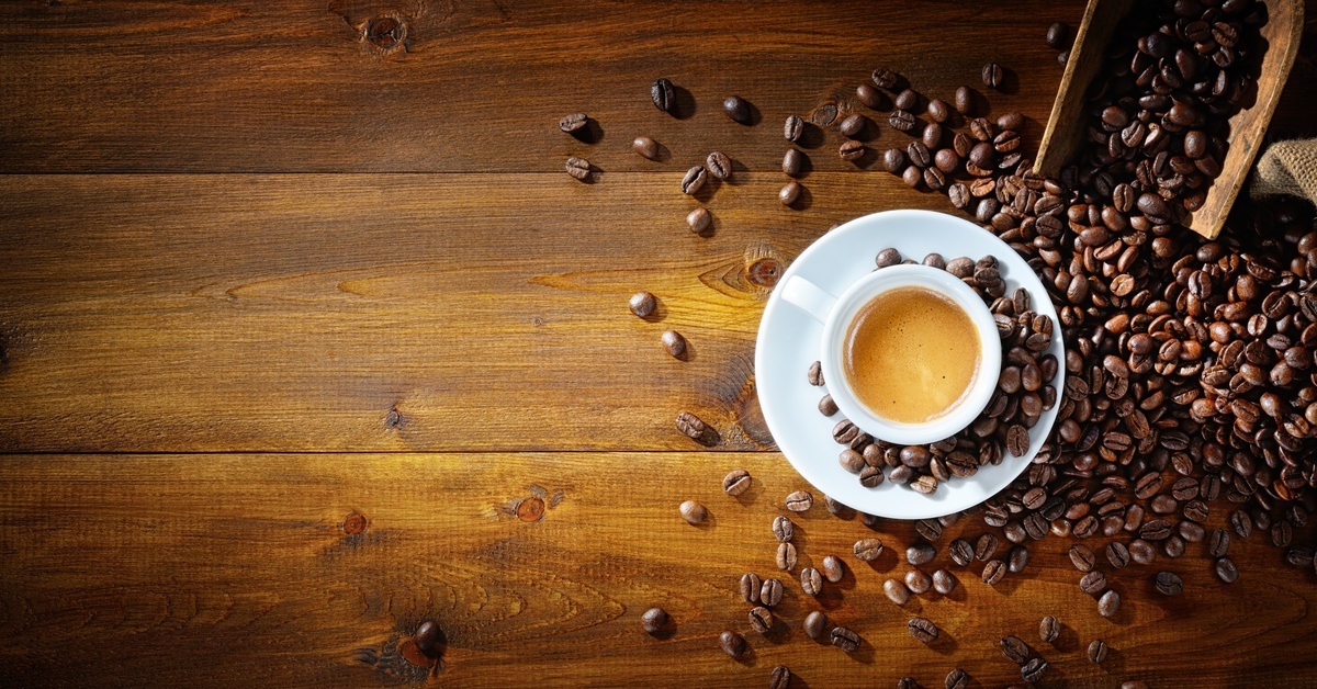 What You Need To Know About Single-Origin Coffee Beans A bunch of coffee beans spilled on the table, with a single cup of coffee sitting next to the beans.